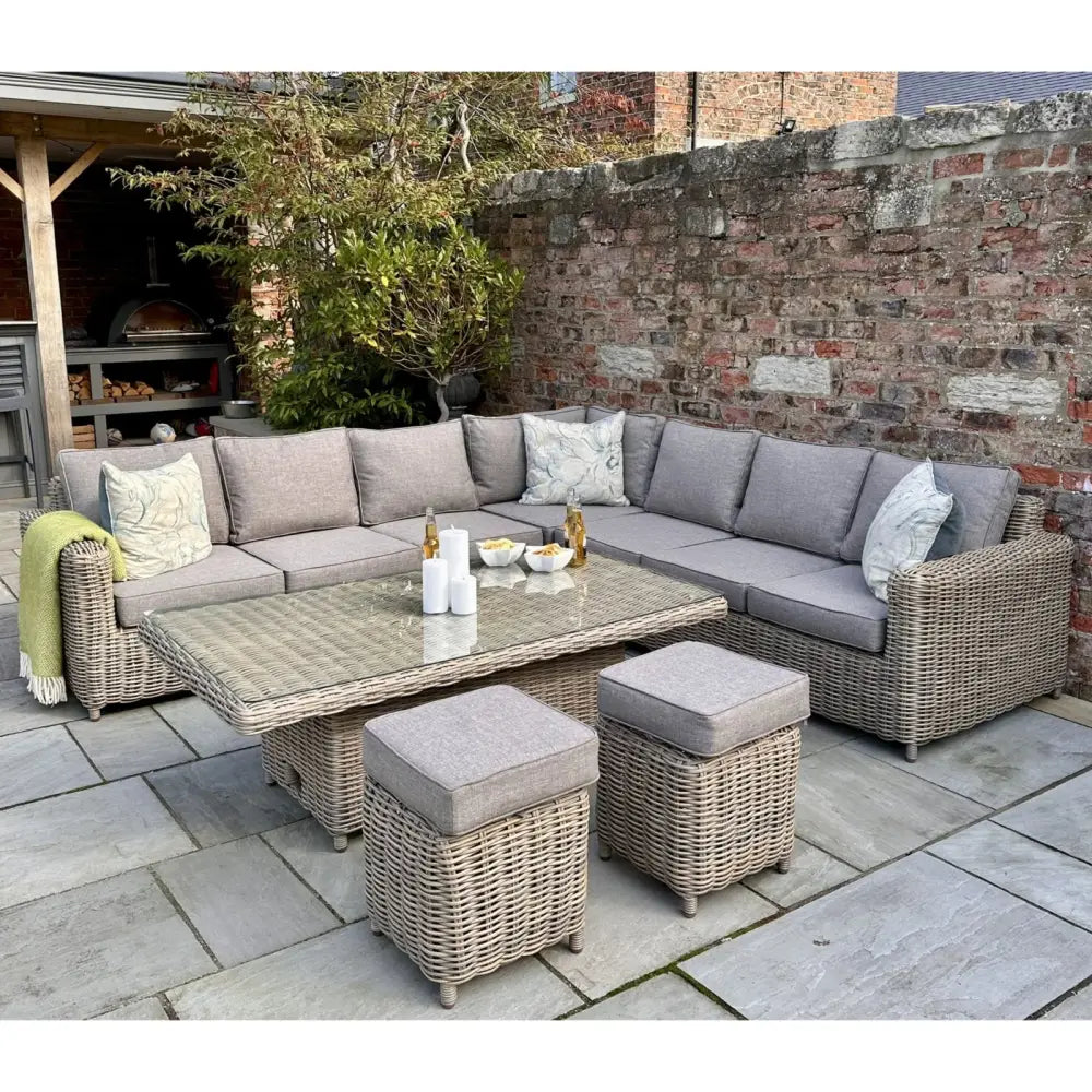 Gray wicker corner set with soft gray fabric cushions featuring a riser table and matching ottomans for outdoor use