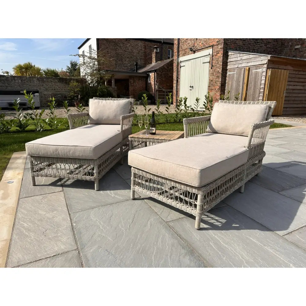Pair of beige cushioned wicker chaise lounges with matching woven side table from provence collection lounger set