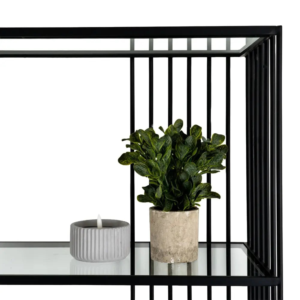 Small artificial green plant in beige ceramic pot on alto shelf unit with clear glass shelves