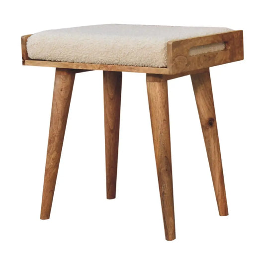 A cozy boucle cream tray style footstool with cream tray sheepskin cushioning and natural wood tapered legs