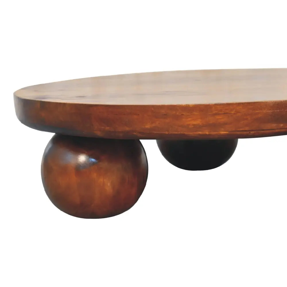 A sleek chestnut central ball table with an oval wooden top and rounded ball legs in rich brown finish