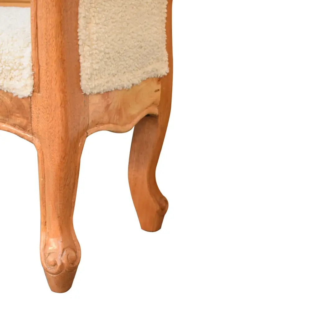 Cream boucle french style bench with light brown wooden side table featuring curved legs and cream sheepskin panels
