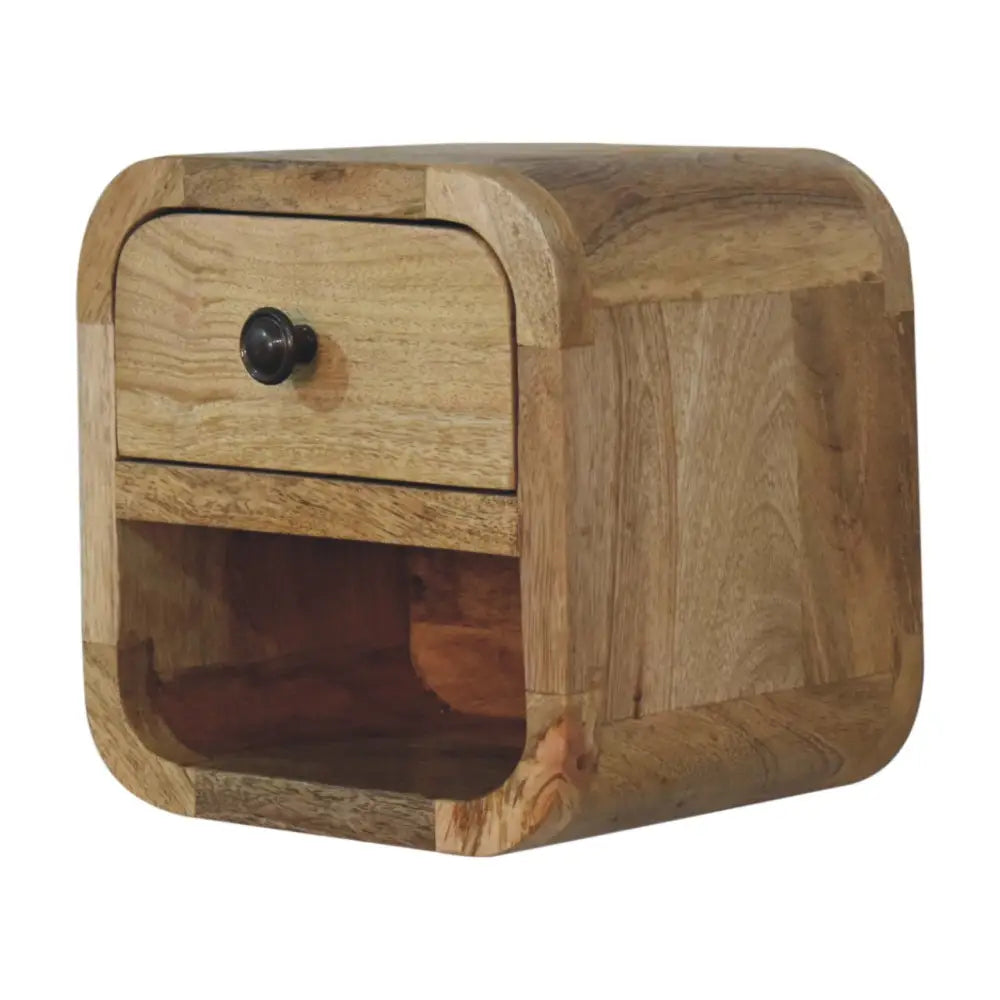 A rustic extra mini curved oak-ish bedside nightstand with one drawer and black metal knob in warm wood tones