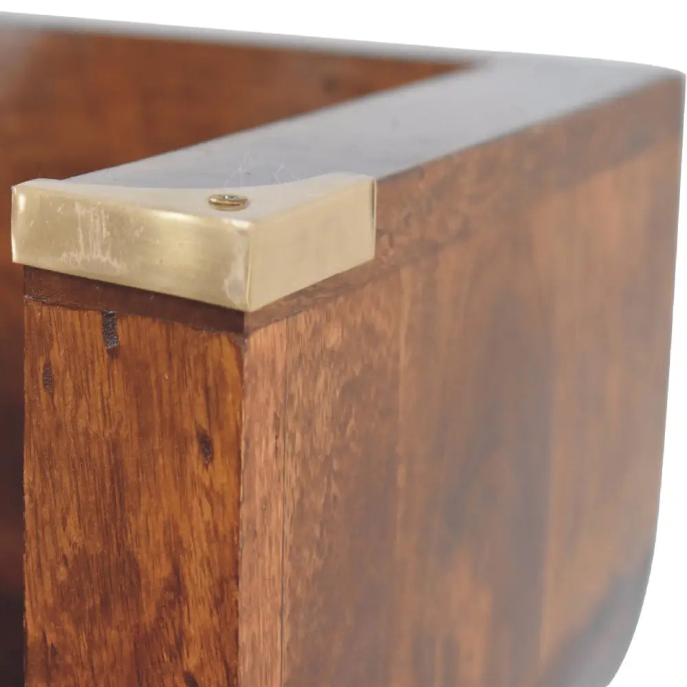 Rich brown wooden leg with polished brass corner cap on the indira chestnut floating console