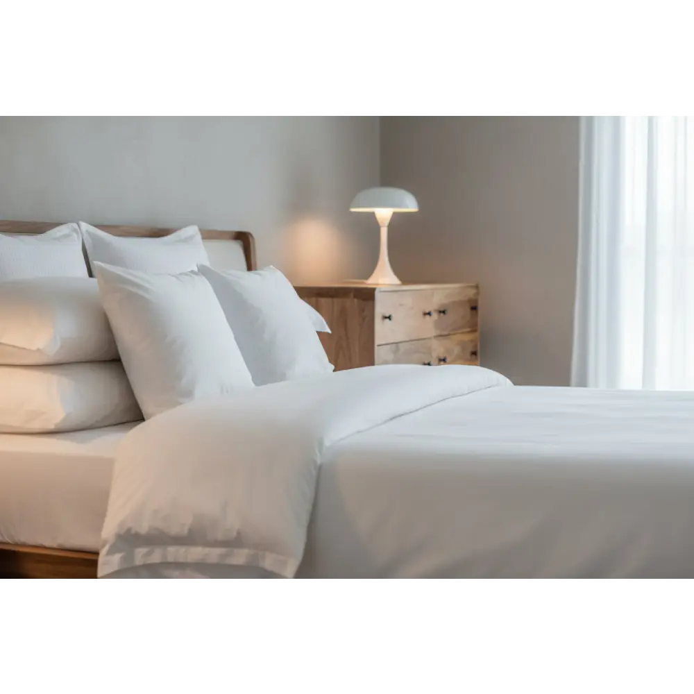 A minimalist white bedside lamp with a dome shade on a wooden nightstand next to a large curved oak-ish chest opulent furniture
