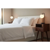 White bed with crisp linens and pillows next to a mini cherry bedside for cozy bedroom style
