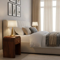 Cream-colored tufted upholstered bed with matching headboard and pillows next to a darcy chestnut nightstand with curved edges and solid mango wood