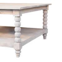 A rustic white-washed spindle acid wash coffee table with turned bead legs and a lower shelf