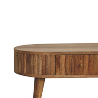 A rustic wooden stripe coffee table with a rounded top vertical slat sides and a single drawer with brass knob